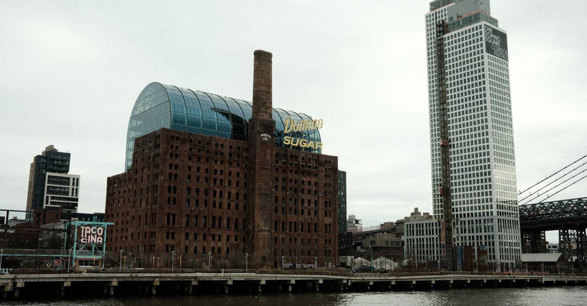 Historical Domino Sugar Refinery by the riverfront in Brooklyn with modern skyscrapers, NYC.